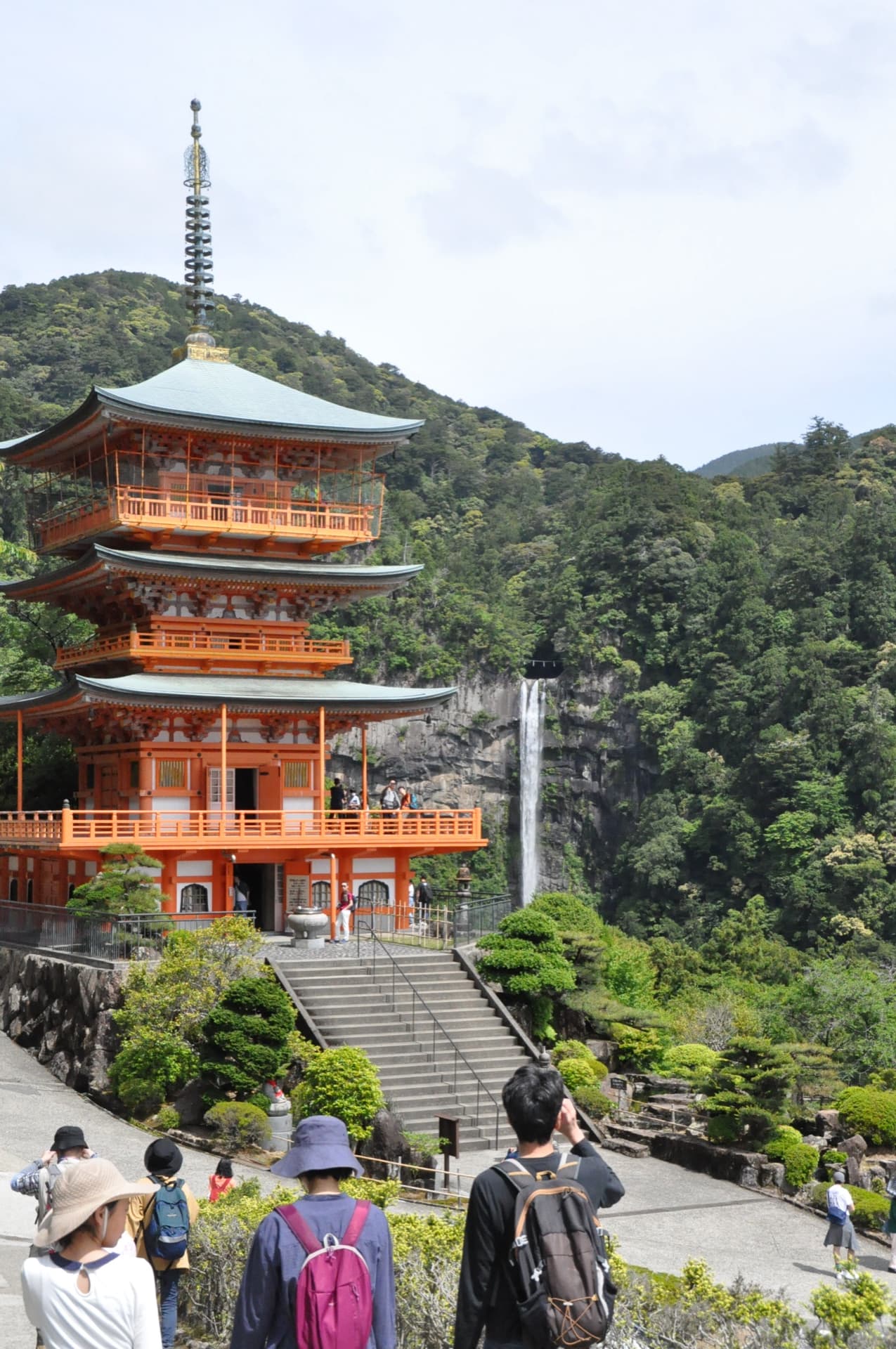 A thin white falls behind a vermilion pagoda