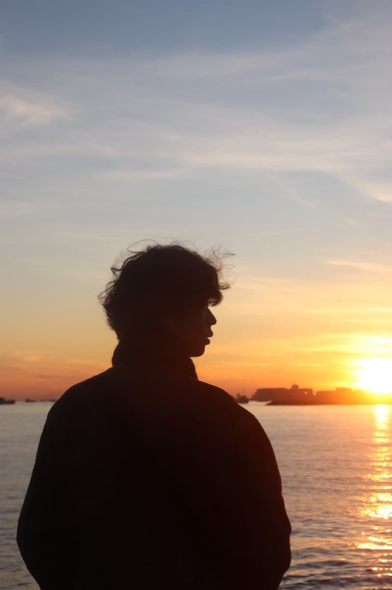Kai silhouetted against a sunset over the water